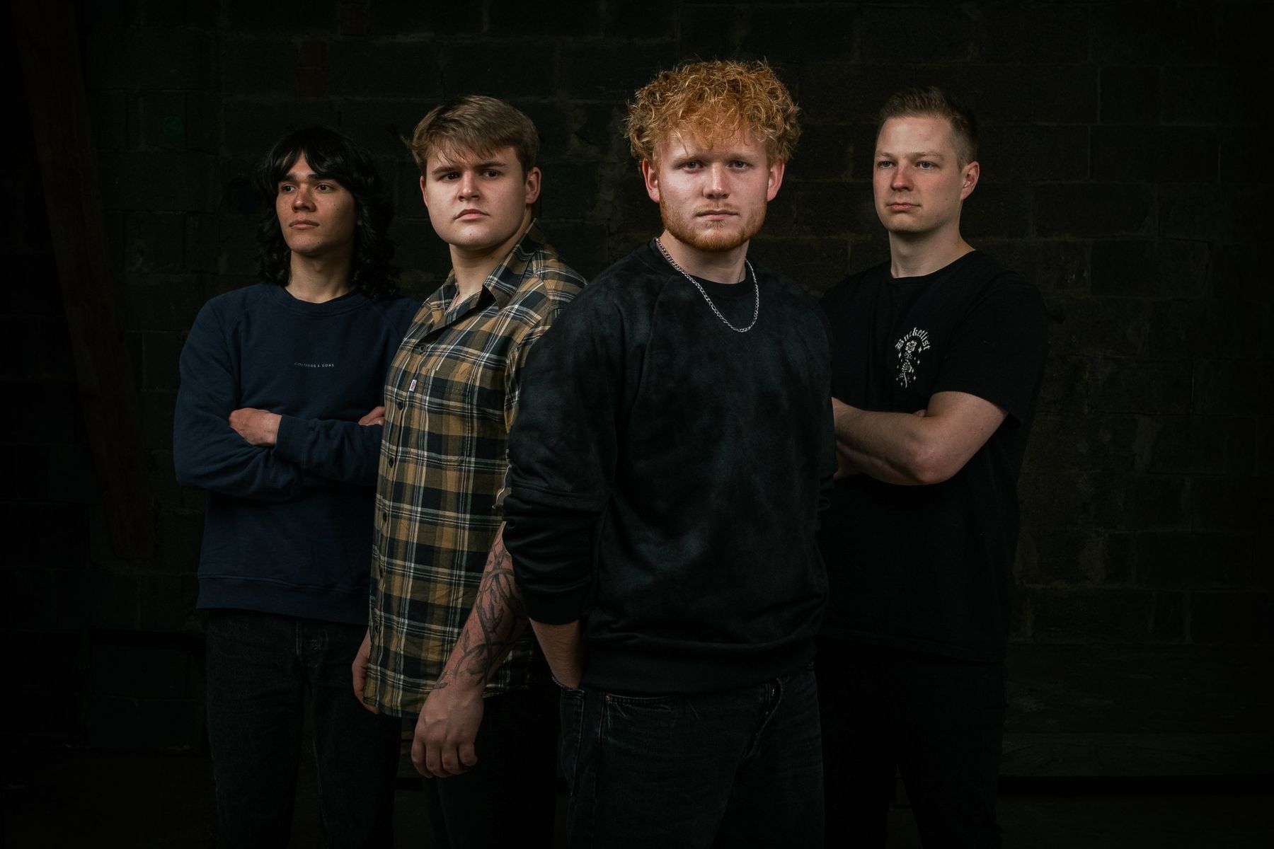 Purple Trees: Melvin, Jakob, Jano und Ayke vor einer dunklen Steinwand
